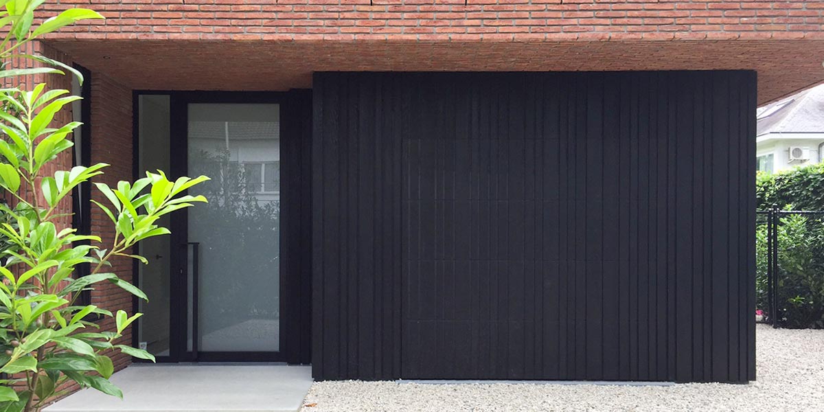 https://garagedeuren2.s3.eu-central-1.amazonaws.com/20180809075342/Zwarte-houten-sectionaal-garagedeur-verticaal-geprofileerd-header1.jpg