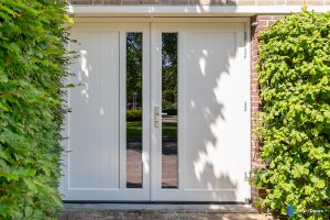 Witte houten openslaande garagedeuren met glas