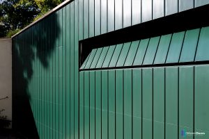 Houten sectionaaldeur gelijk met de gevel groen