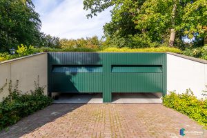 Houten sectionaaldeur gelijk met de gevel groen