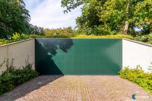 Houten sectionaaldeur gelijk met de gevel groen