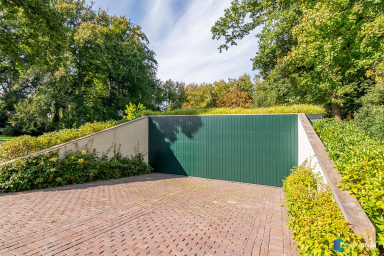 Houten sectionaaldeur gelijk met de gevel groen